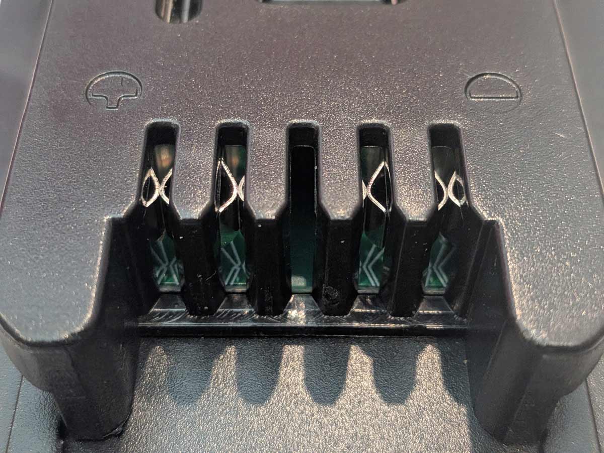 Ozito 18V PXC to Milwaukee M18 battery adapter - close-up of the Milwaukee tool-side terminals with plus and minus marks